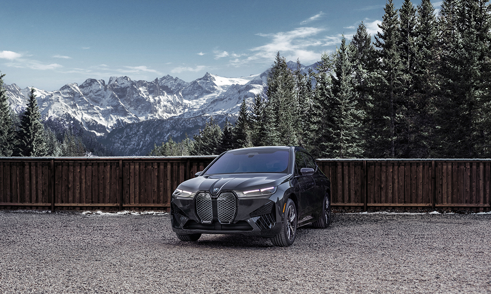 The 2024 BMW iX xDrive50 parked in front of a beautiful wintry mountain landscape