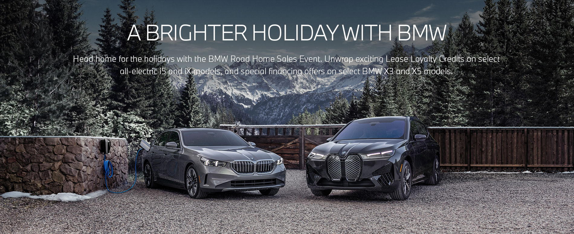 The 2024 i5 eDrive40, plugged into a BMW Wallbox charger, and the 2024 iX xDrive50 parked in front of a beautiful wintry mountain landscape