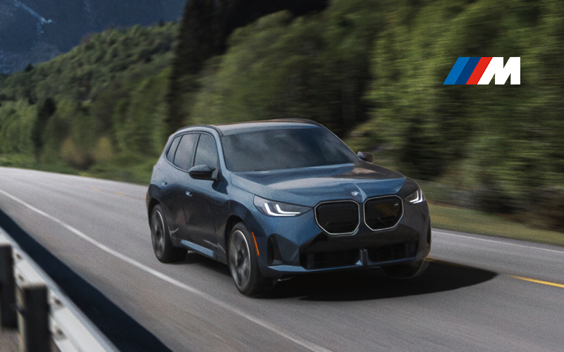  The BMW X3 M50 driving around a mountainous curve.
        