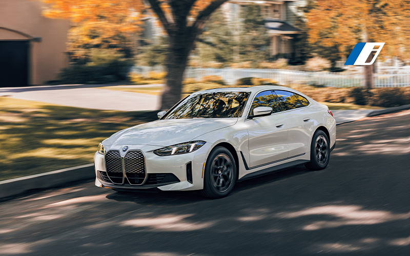  The BMW i4 driving down a neighborhood road.
       