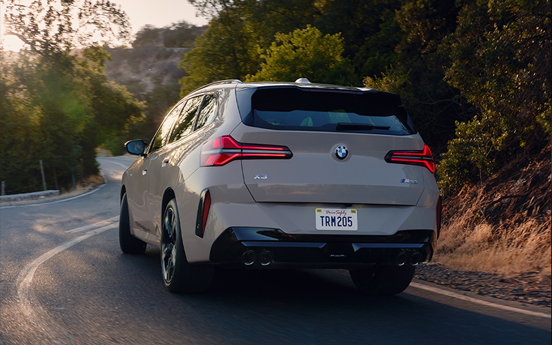 Rear view shot of the BMW X3 driving on a road.