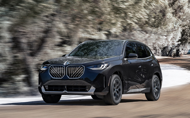 BMW X3 driving on a neighborhood road.