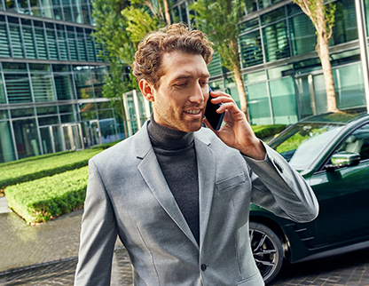 Alt Text – A man speaks on a phone with a BMW parked in the background