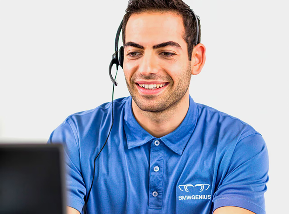 A BMW Genius worker on a headset looking at a computer.