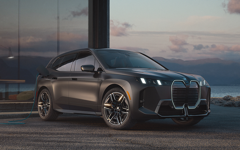 The BMW iX M70 parked with an ocean background.