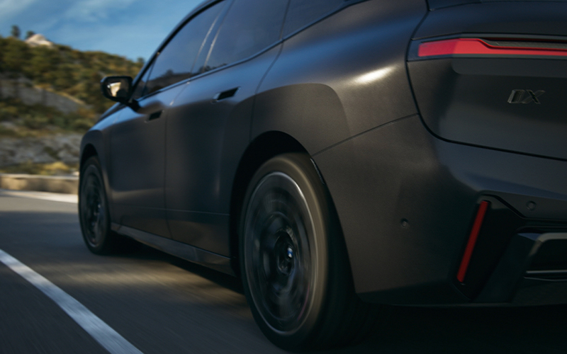  Side angle shot of the BMW iX M70 driving down road.