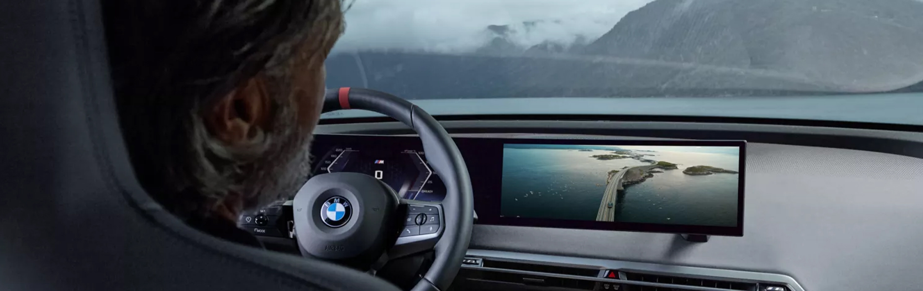 Man sitting in front seat with dashboard view of the BMW iX M70.