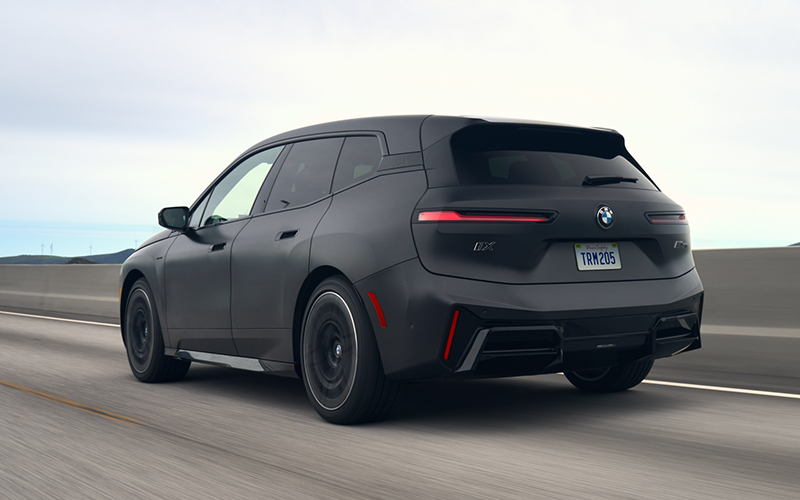 The BMW iX M70 driving rear shot.