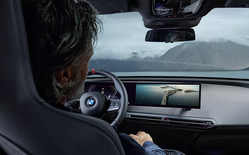 Man sitting in front seat with dashboard view of the BMW iX M70.