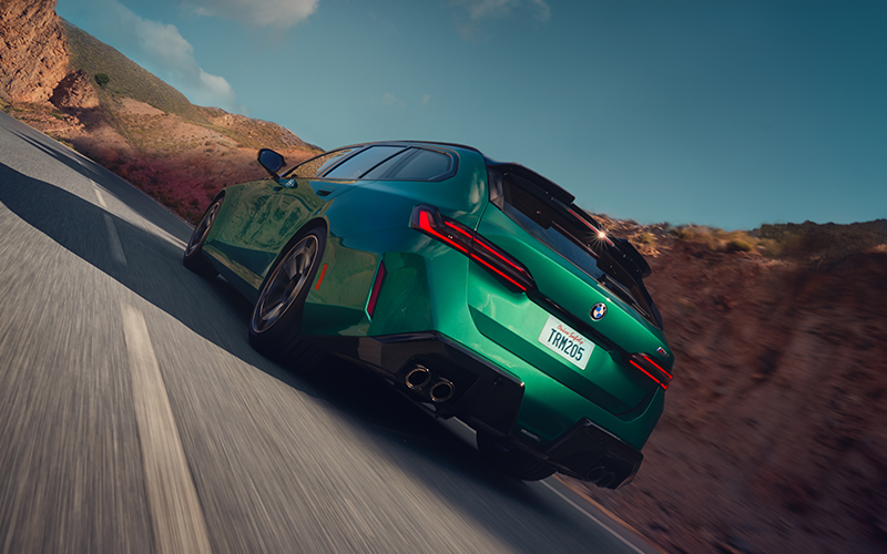 Rearview shot of a green BMW M5 Touring driving down a road.