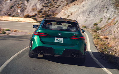 Rearview shot of a BMW M5 Touring driving down a mountainous road.