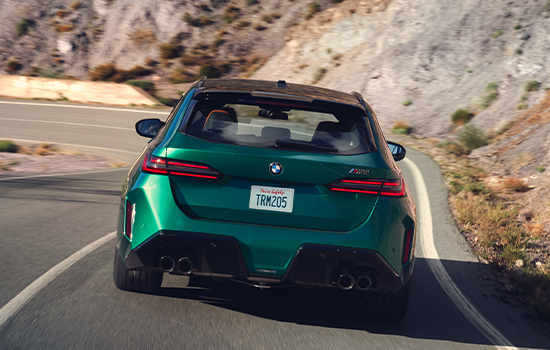 Rearview shot of a BMW M5 Touring driving down a mountainous road.