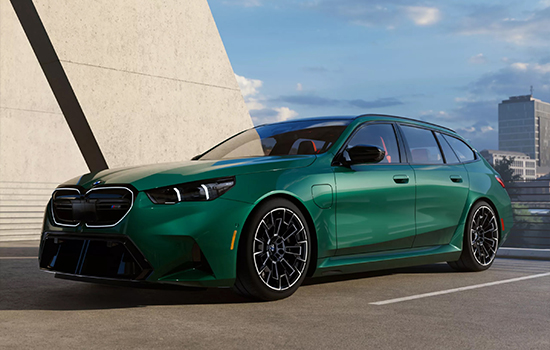 Green BMW M5 Touring driving on a city road.