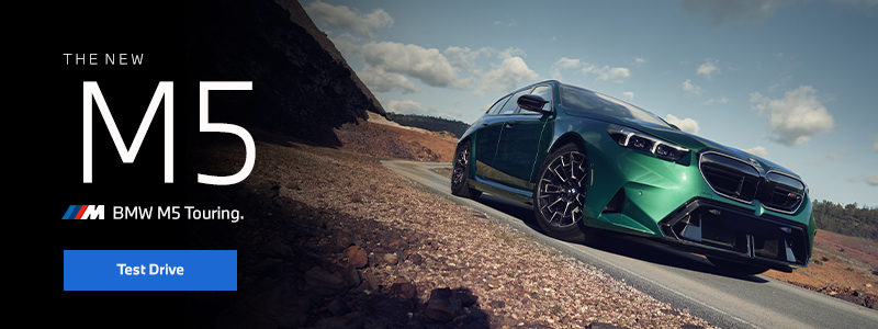  The new BMW M5 Touring in green driving down desert road.