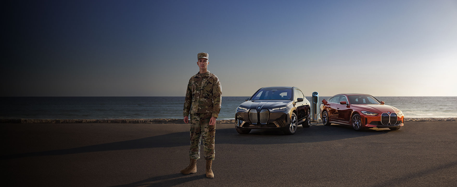 Military man in front of BMW iX and i4 with a
beach setting.