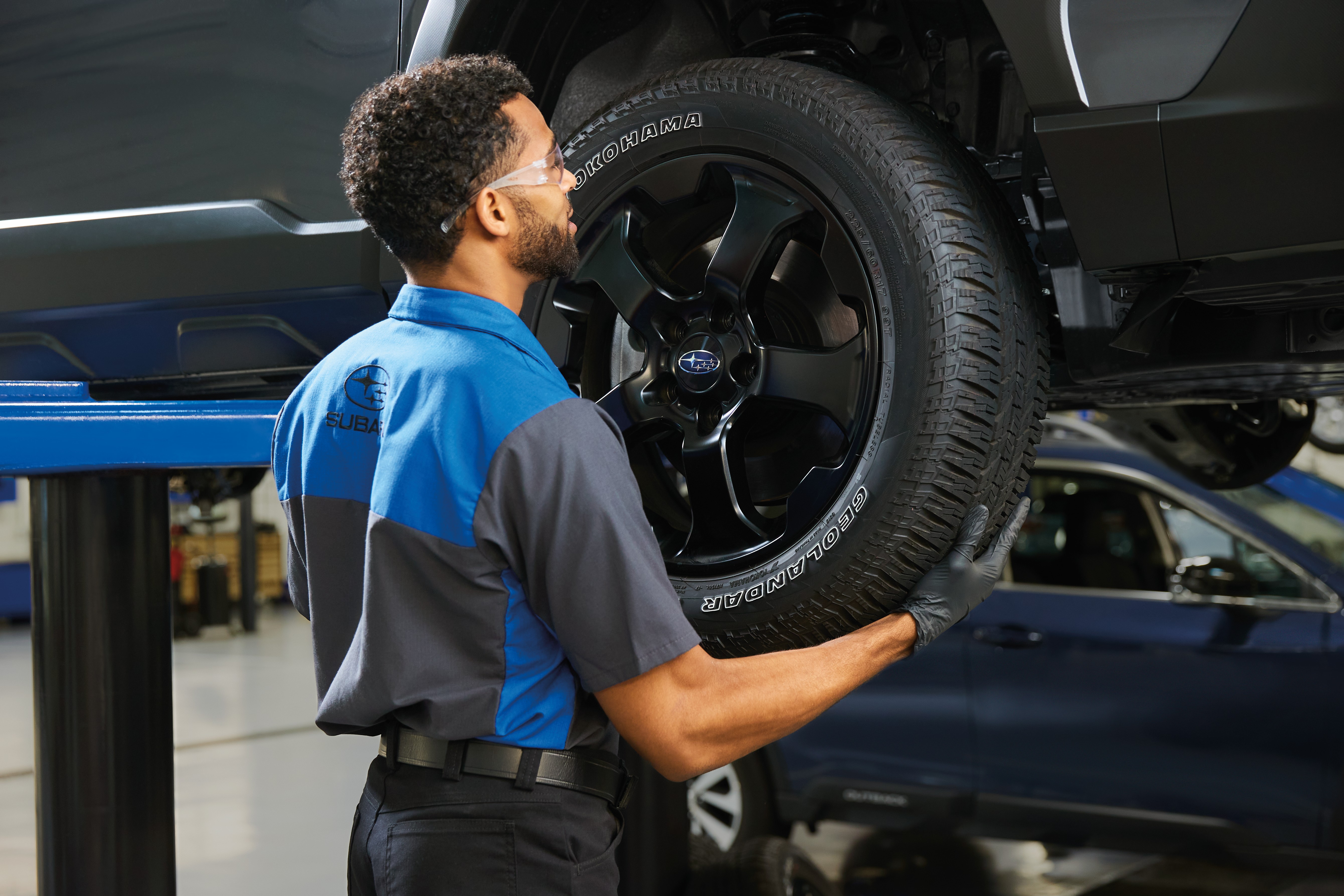 A Subaru service technician checking tire air pressure.