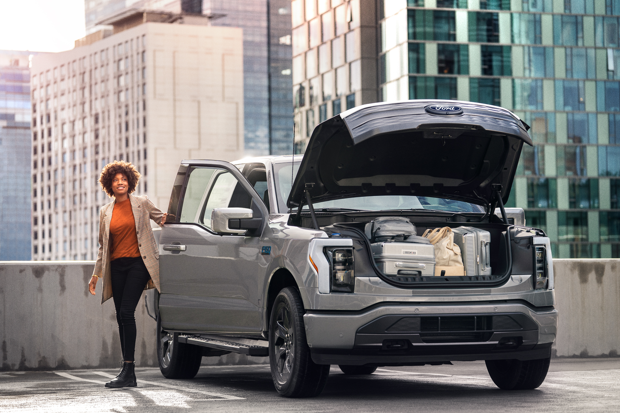 A woman loads the front trunk of a Ford F-150 Lightning® with supplies