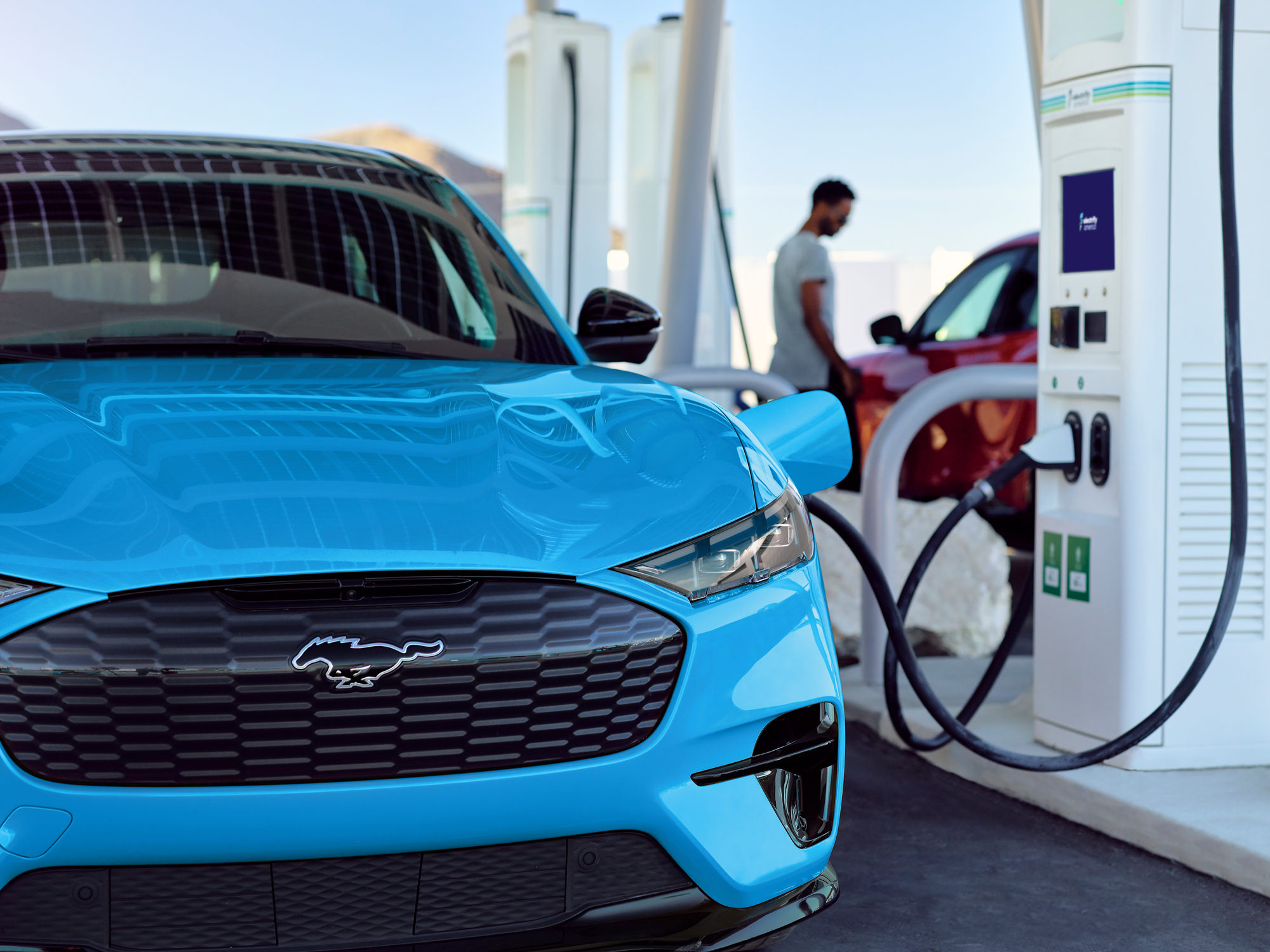 A Ford Mustang Mach-E in grabber blue at a public charge station getting charged