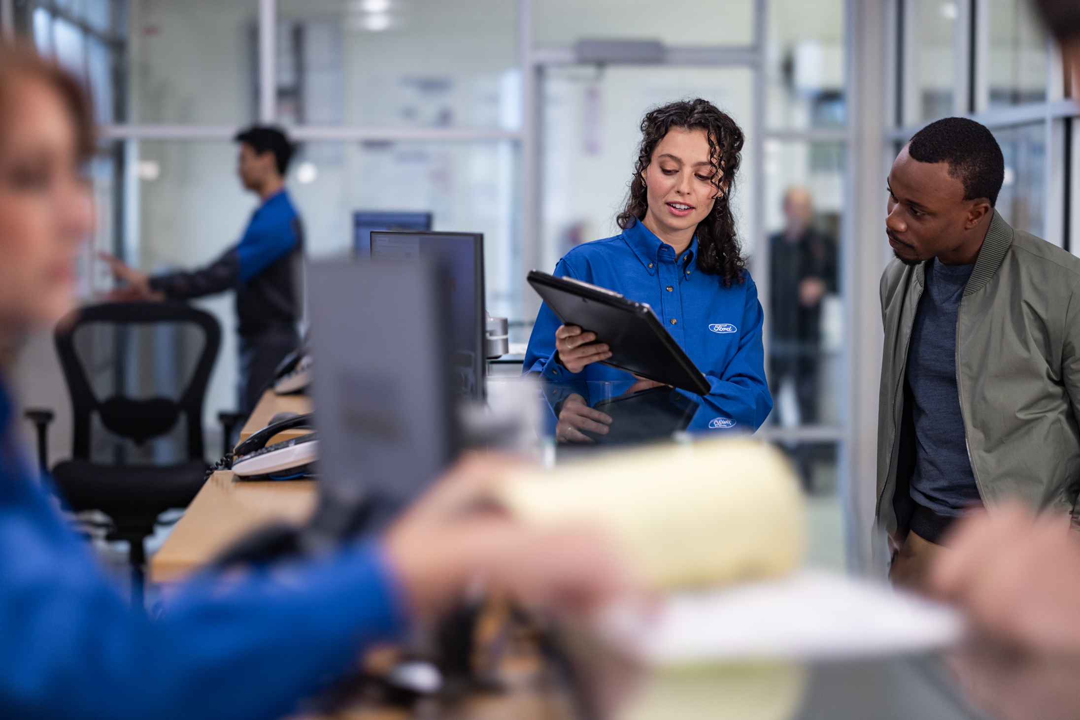 A Ford employee showing a customer information on a tablet.