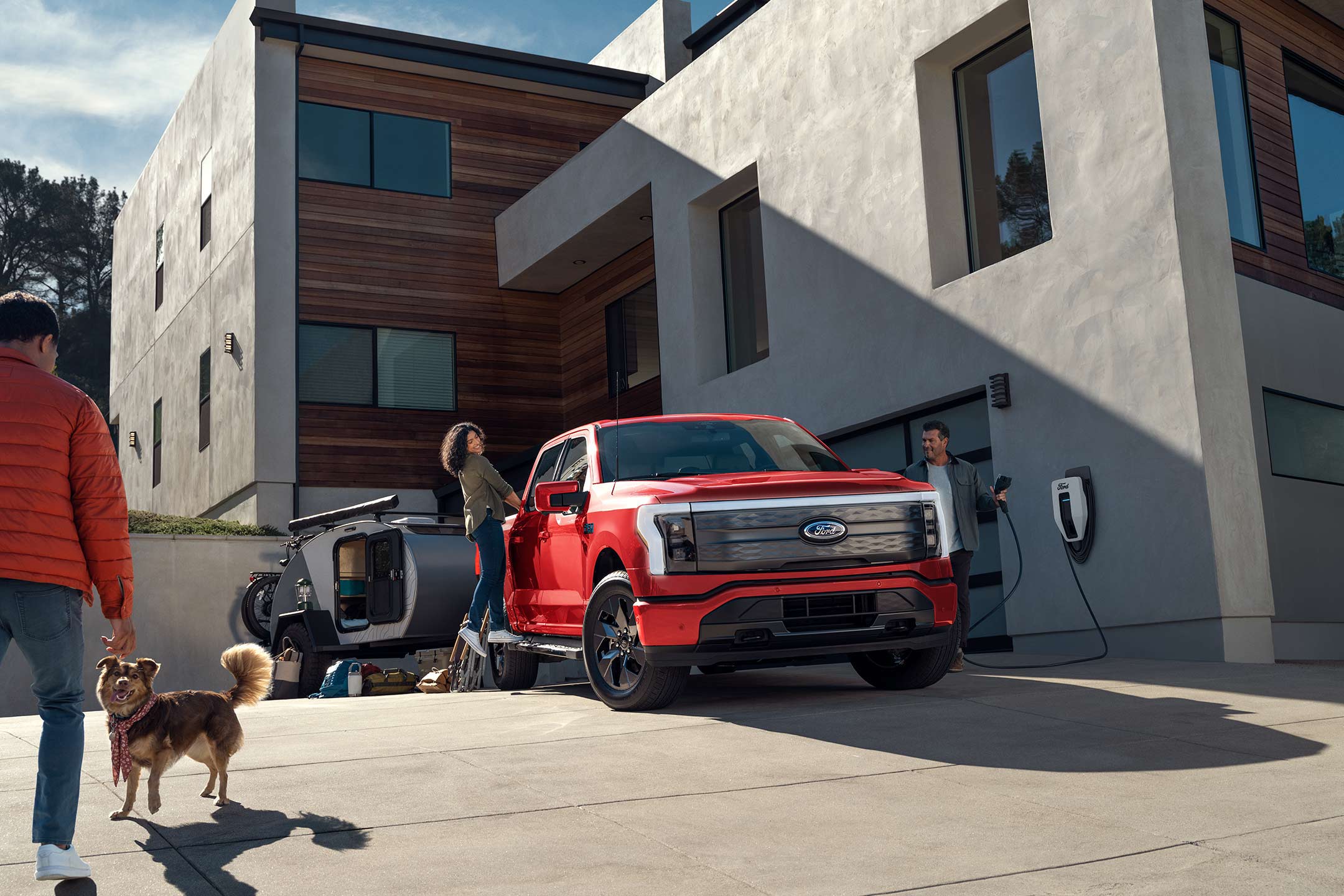 A couple talks to a neighbor as one of them unplugs their F-150 Lightning® from a home charging station