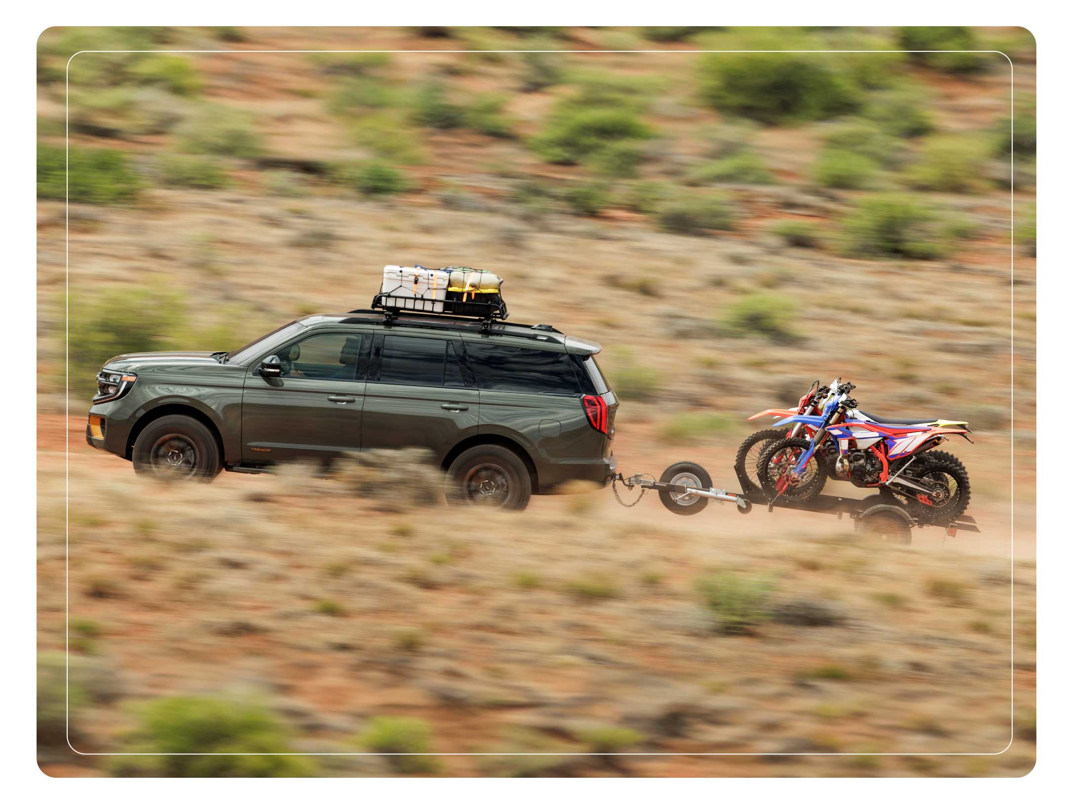 2025 Ford Expedition<sup>®</sup> TREMOR<sup>®</sup> SUV with a driver towing a dirt bike trailer on a desert road