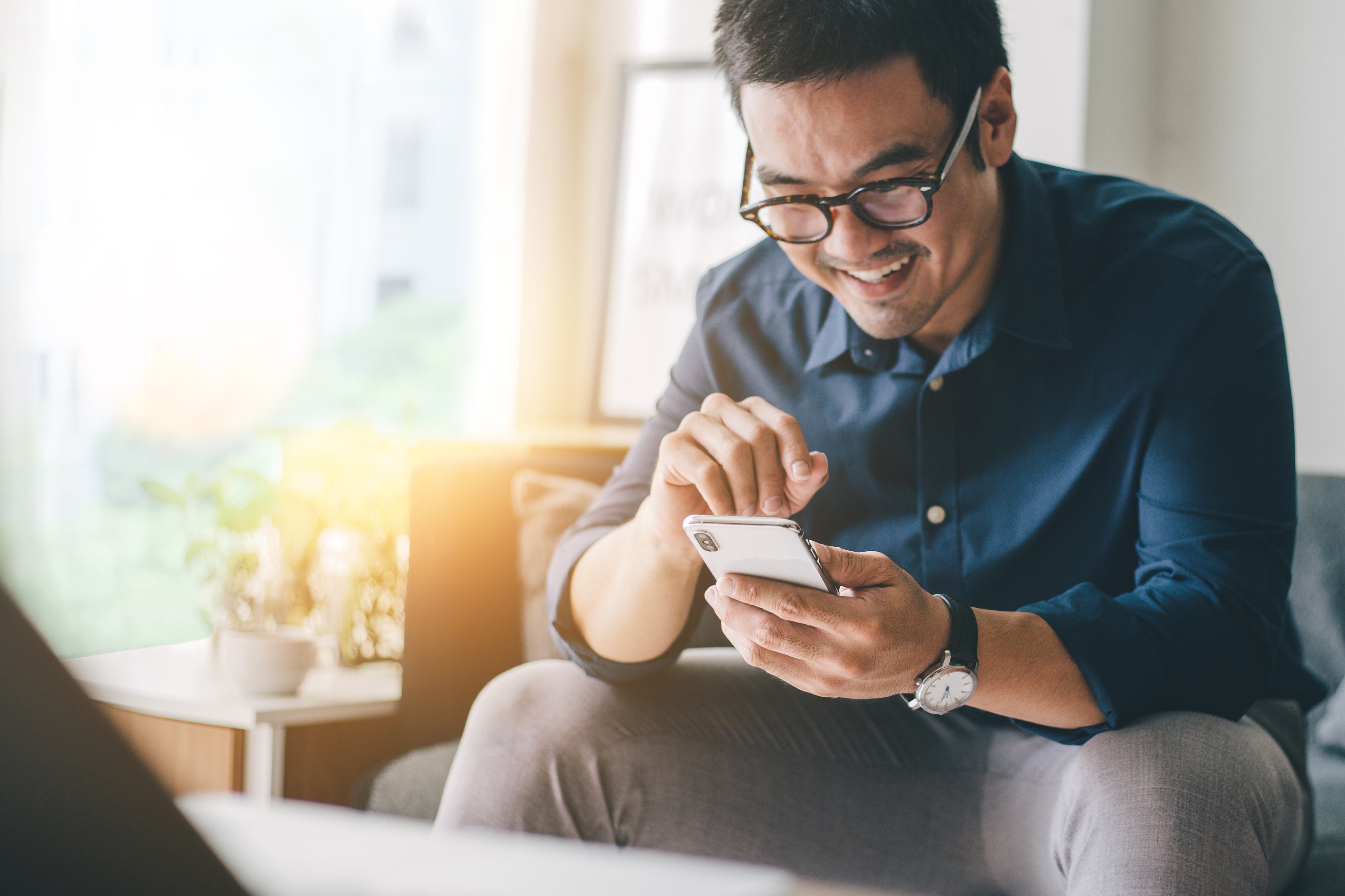 Smiling person in glasses sits in a well-lit room and uses their smartphone to learn
about Flex Buy financing.