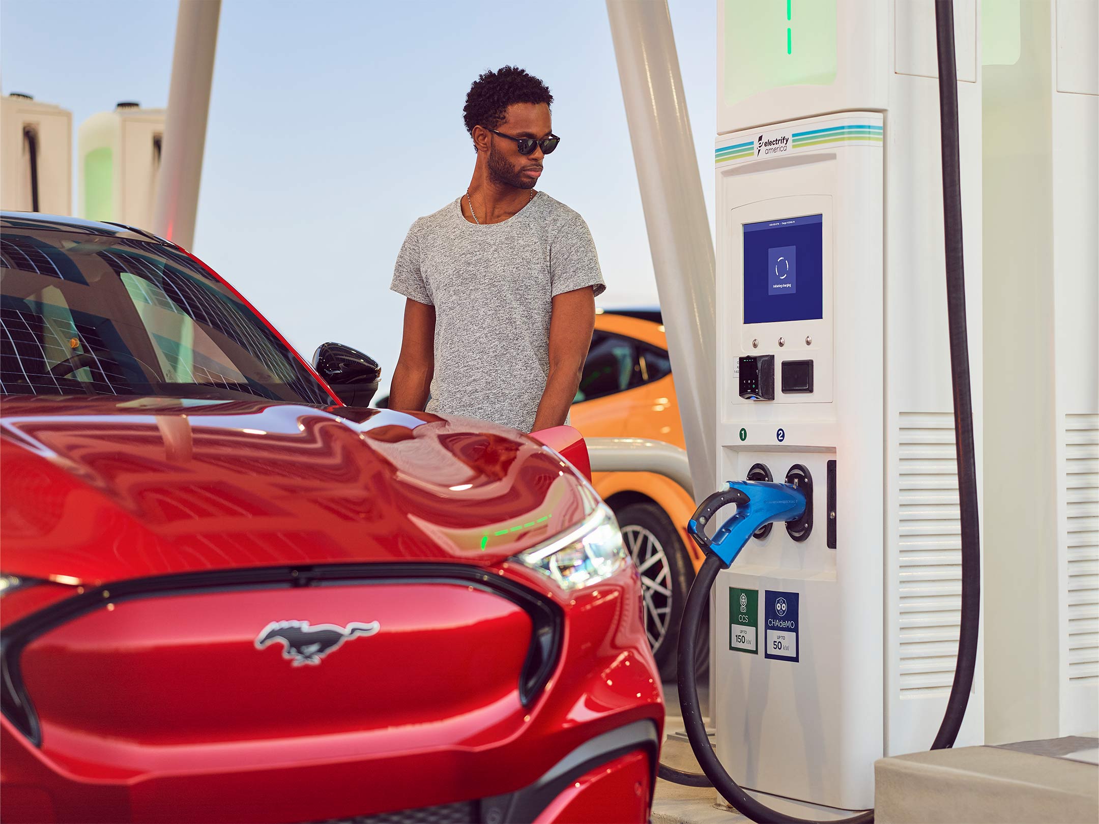 A man plugs in a Mustang Mach-E at a public charging station