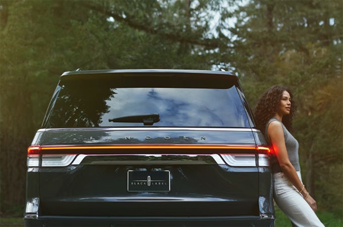 A woman leaning against the Lincoln Navigator® SUV.