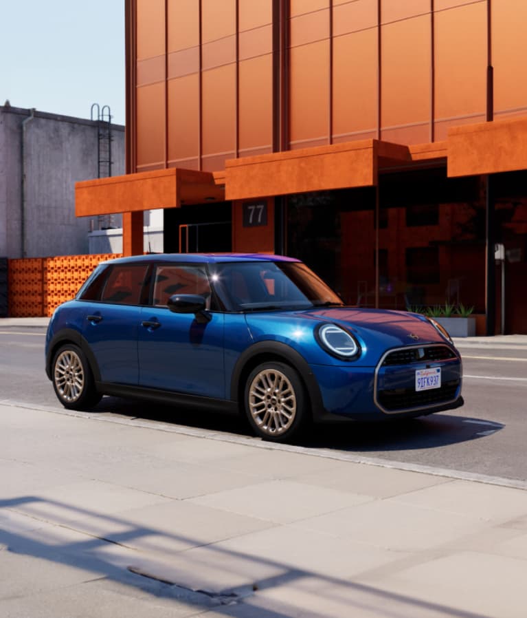 The MINI Cooper S 4 Door parked in front of an orange building.