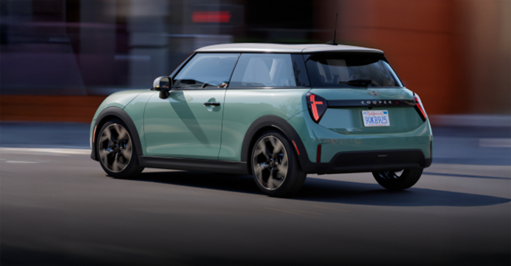 Angled view of the MINI Cooper S 2 Door parallel parked in front of a purple building.