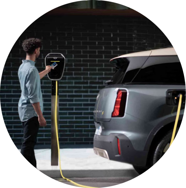 Side-view of a person charging their MINI Countryman SE ALL4 against a brick wall.