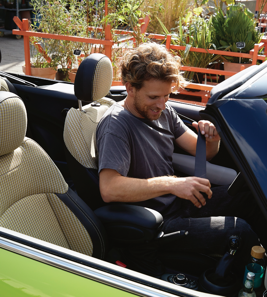 Man buckling himself in to a zesty yellow MINI Convertible