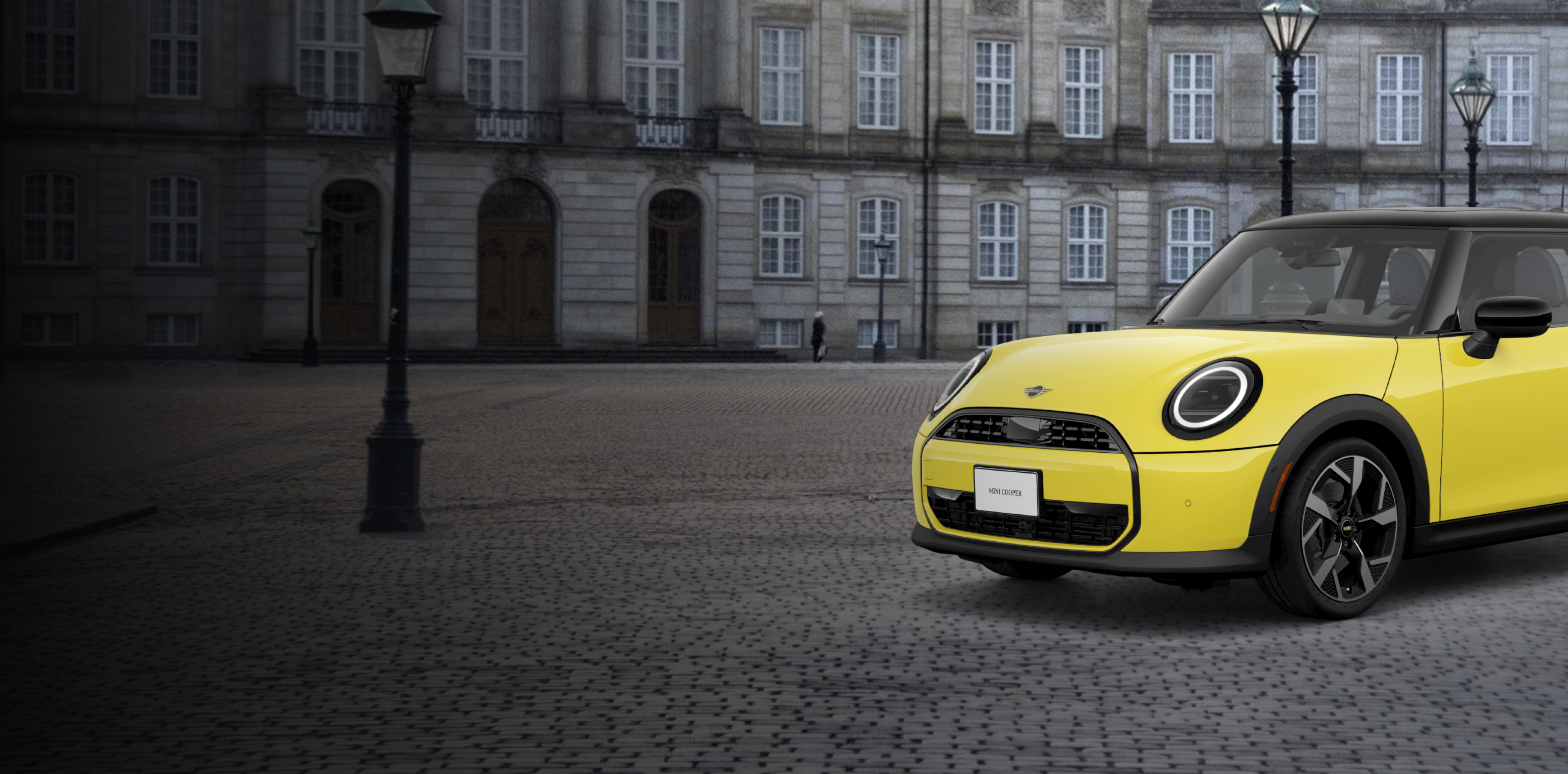 Front side view of a MINI Cooper Oxford Edition parked on a brick street in front of a building.
