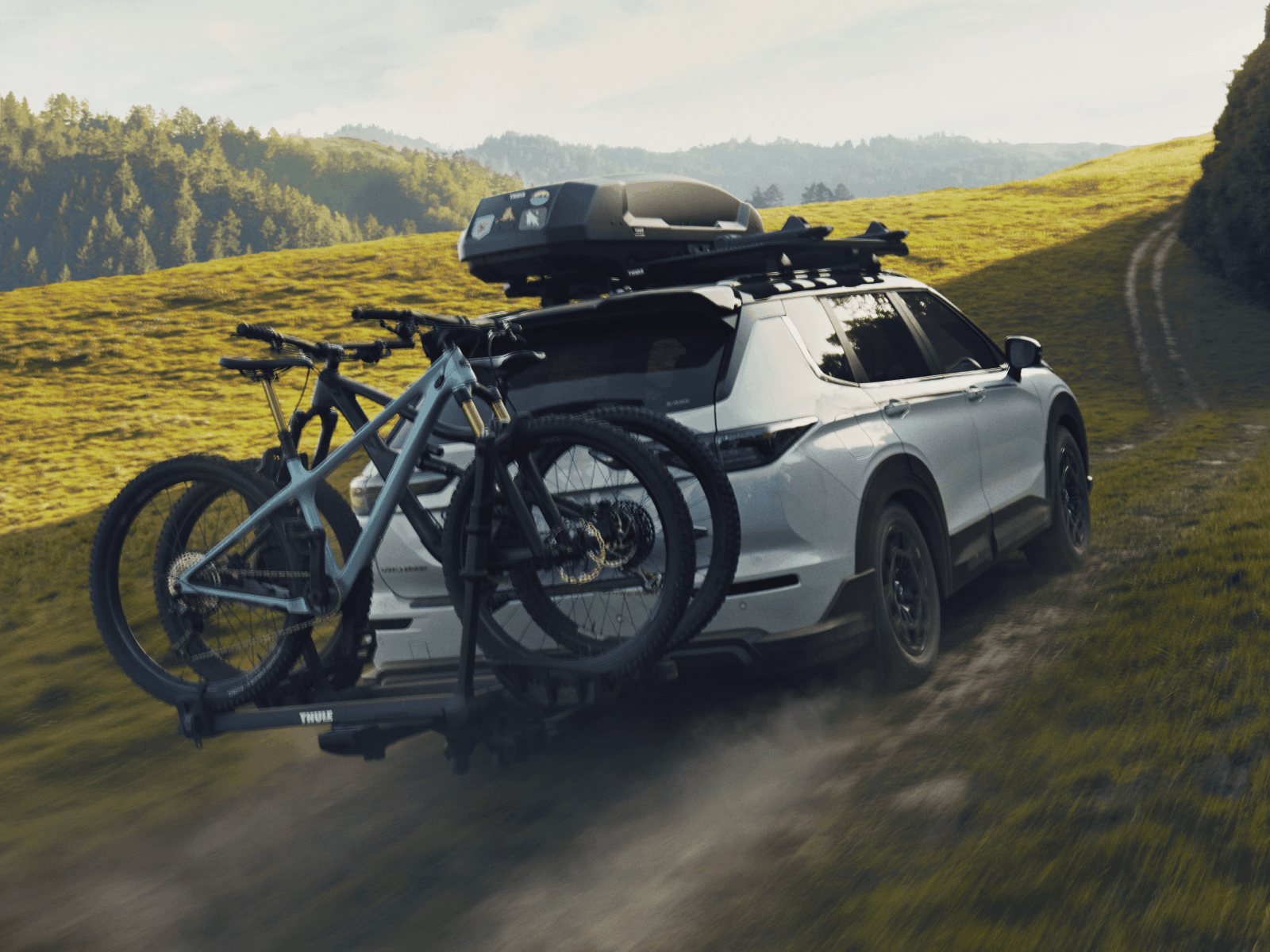 Back of White Mitsubishi Outlander Trail with bikes and roof rack