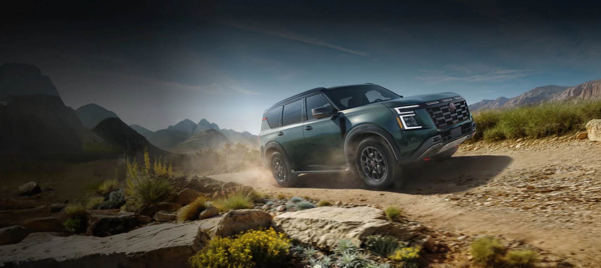 2026 Nissan Rogue driving through the desert scrub on a dirt road