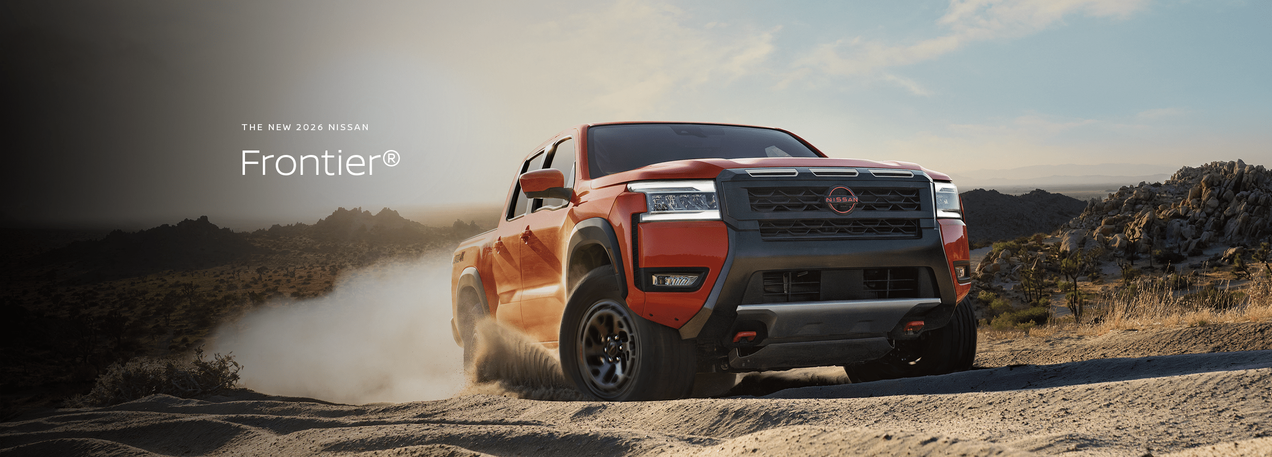 2026 Nissan Rogue driving through the desert scrub on a dirt road