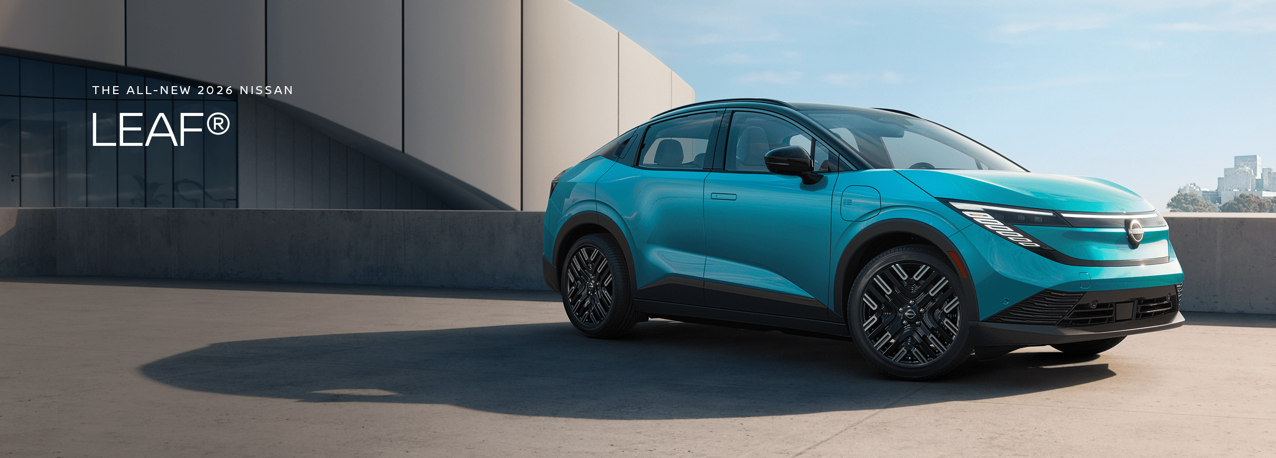 2026 Nissan LEAF in blue parked on a rooftop with modern building the background