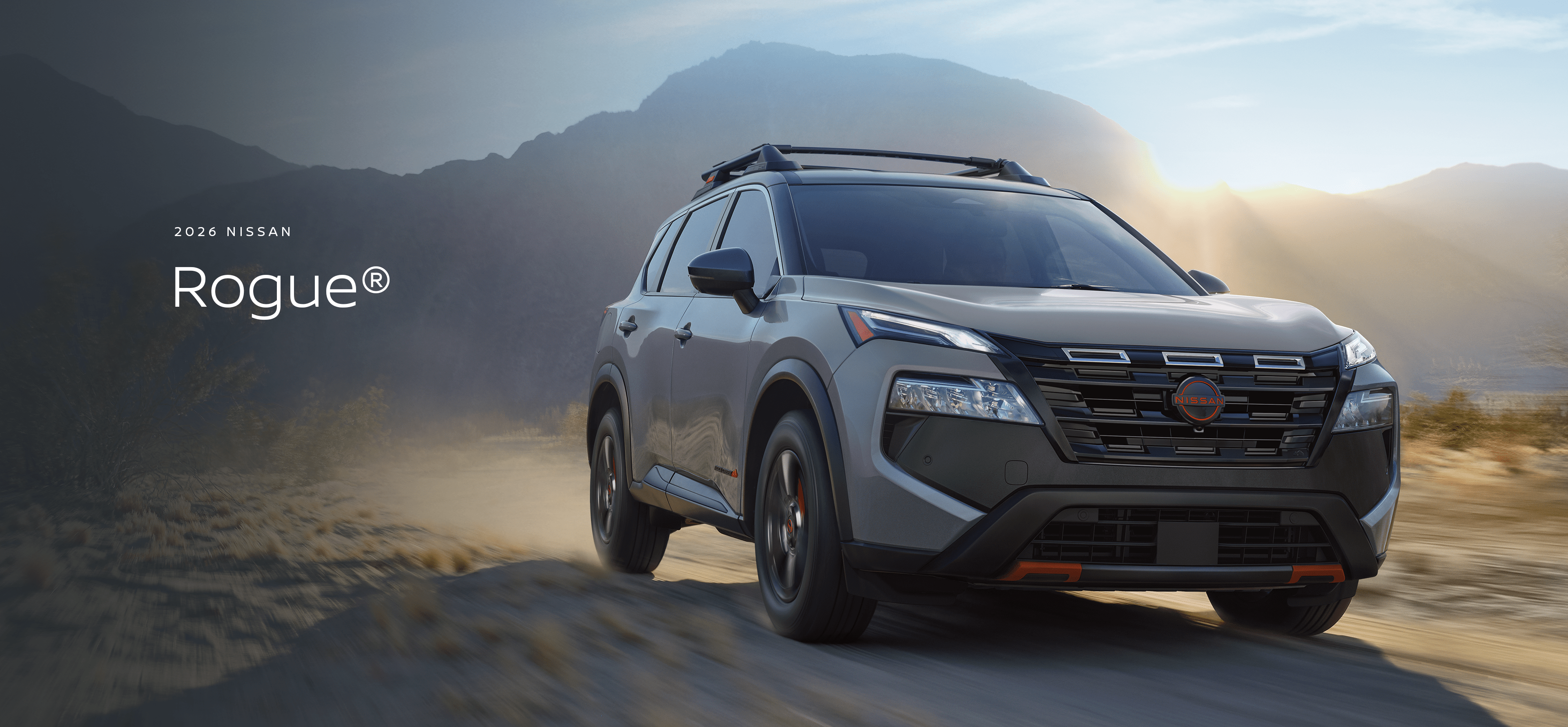 2026 Nissan Rogue driving through the desert scrub on a dirt road