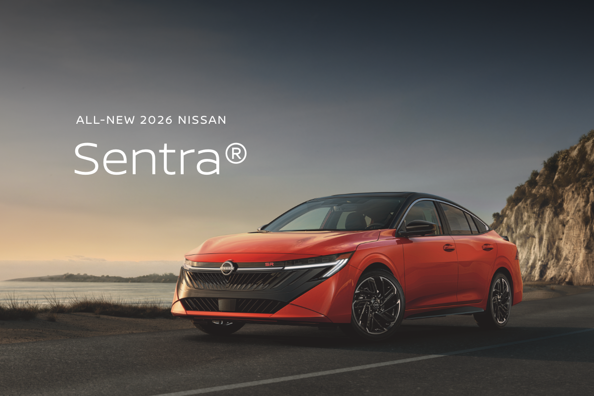 2026 Nissan Sentra in red driving on a desert road with mountains in the distance