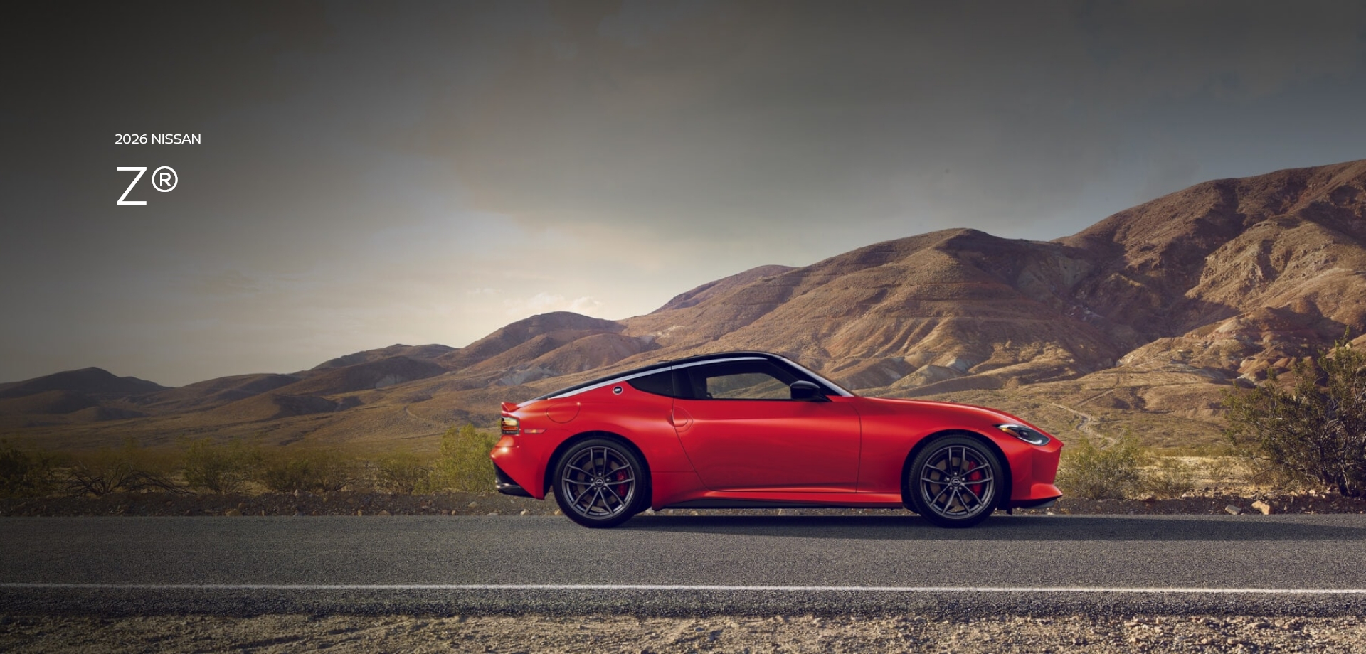 2026 Nissan Z in red driving on a desert road with mountains in the distance