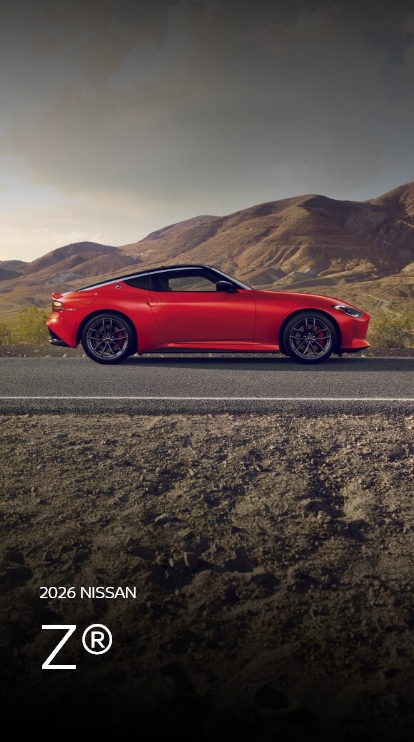 2026 Nissan Z in red driving on a desert road with mountains in the distance