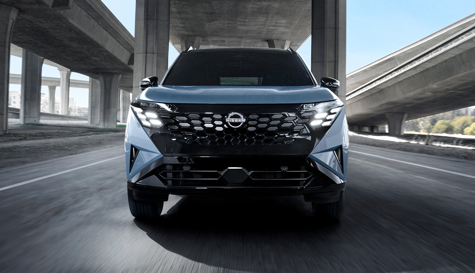 Front view of the 2027 Nissan Rogue Hybrid driving on the road