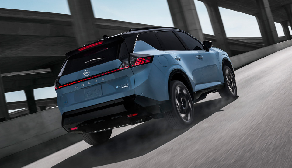 Rear view of the 2027 Nissan Rogue Hybrid driving on the road