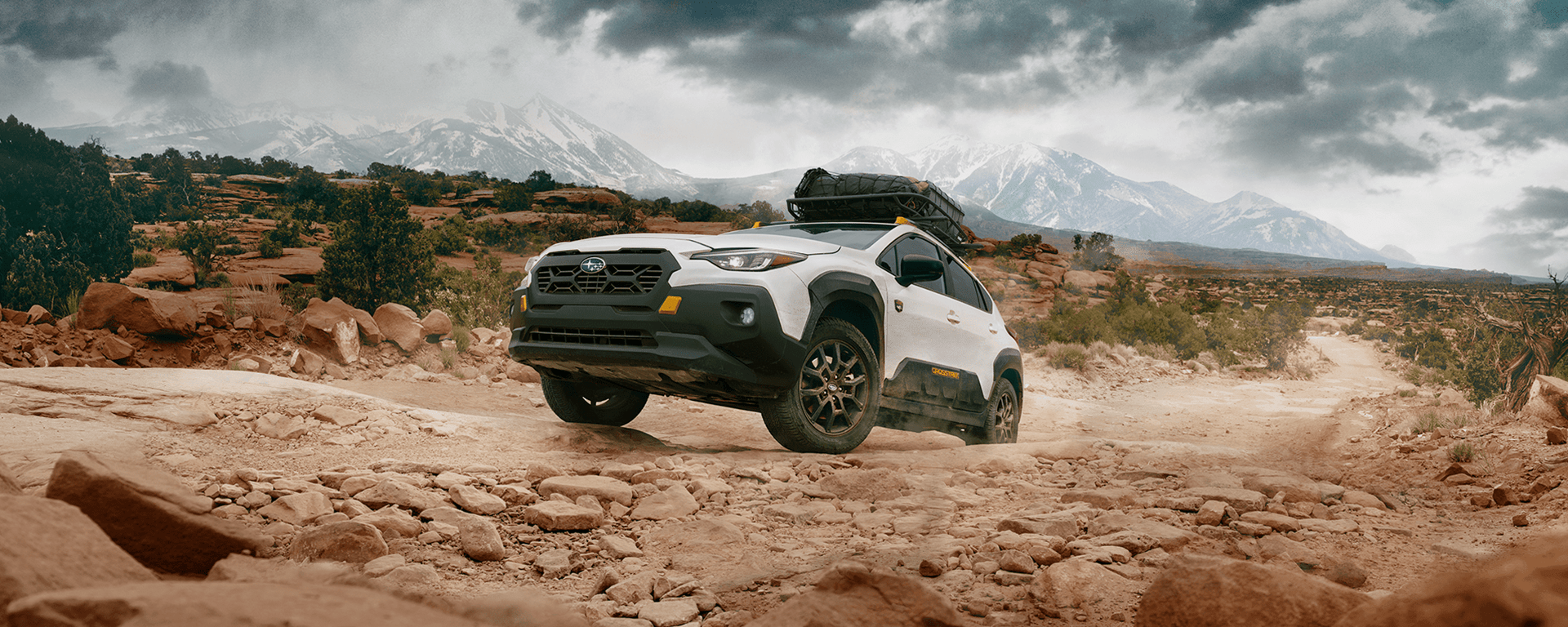 A white Crosstrek Wilderness drives up a rocky canyon