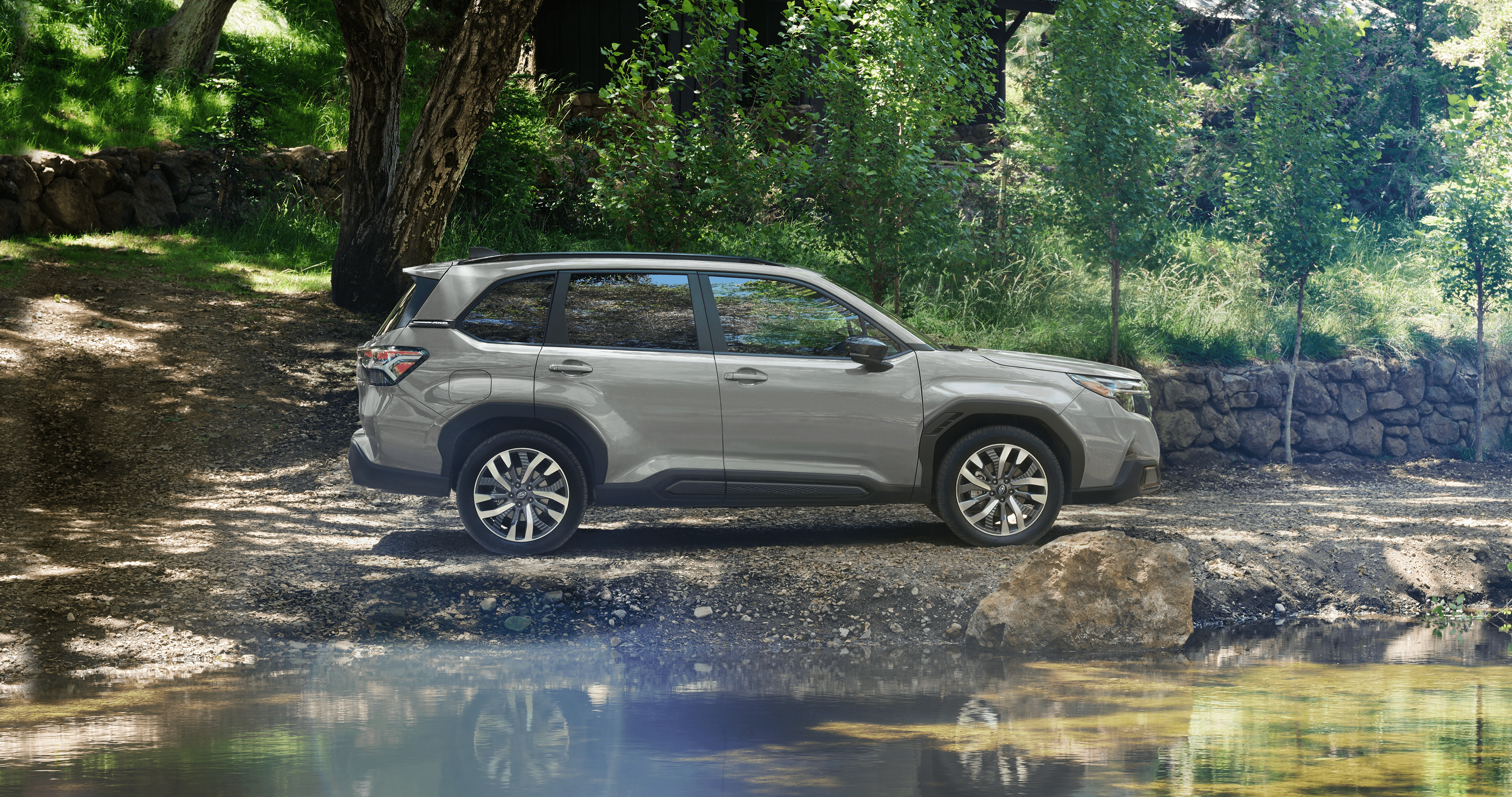 2025 Subaru vehicle parked in the shade alongside a lake