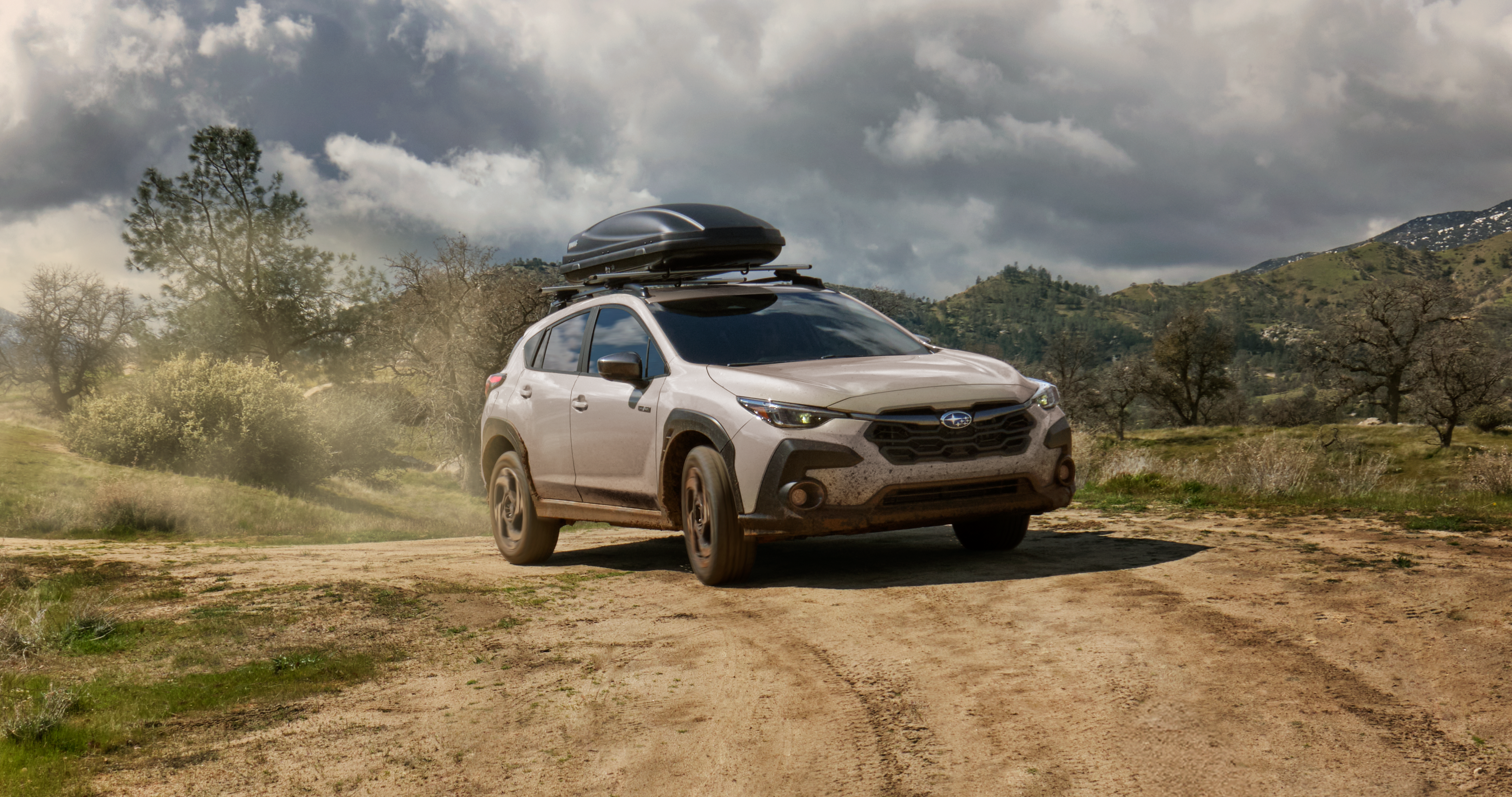 2026 Crosstrek Hybrid parked in a hilly, tree-covered landscape.