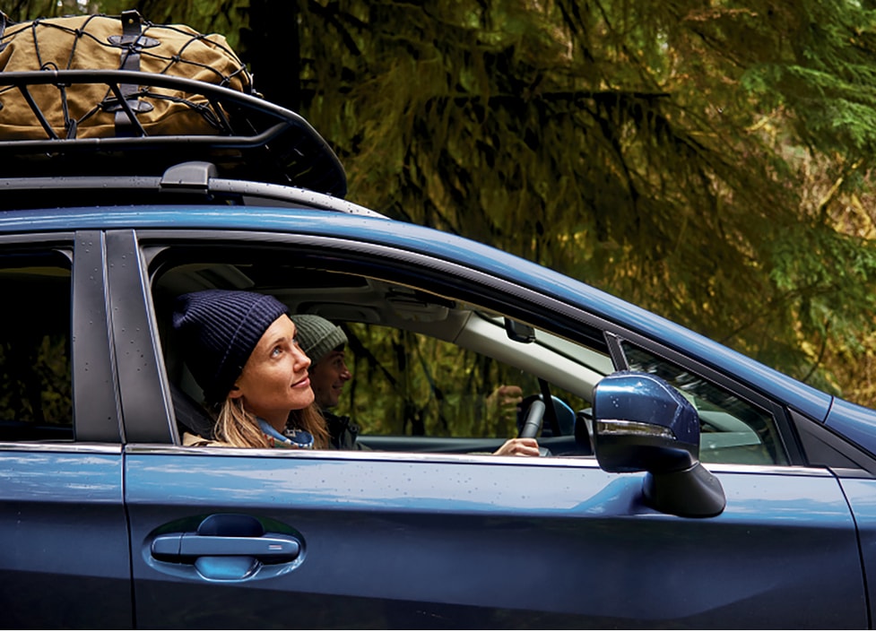 Person looking out passenger front window of a Blue Subaru