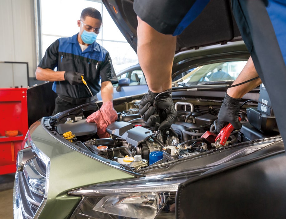 Dos técnicos de Subaru realizan tareas de mantenimiento en el compartimento del motor de un Subaru