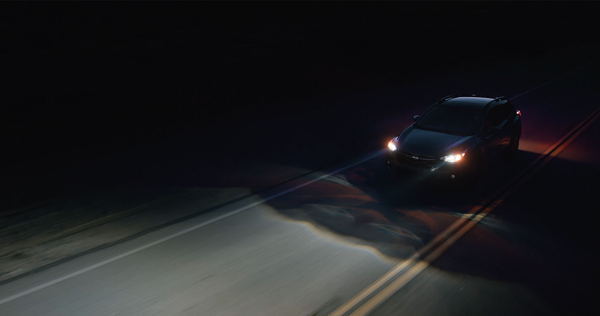 A Subaru driving at night with Advanced Headlights activated.