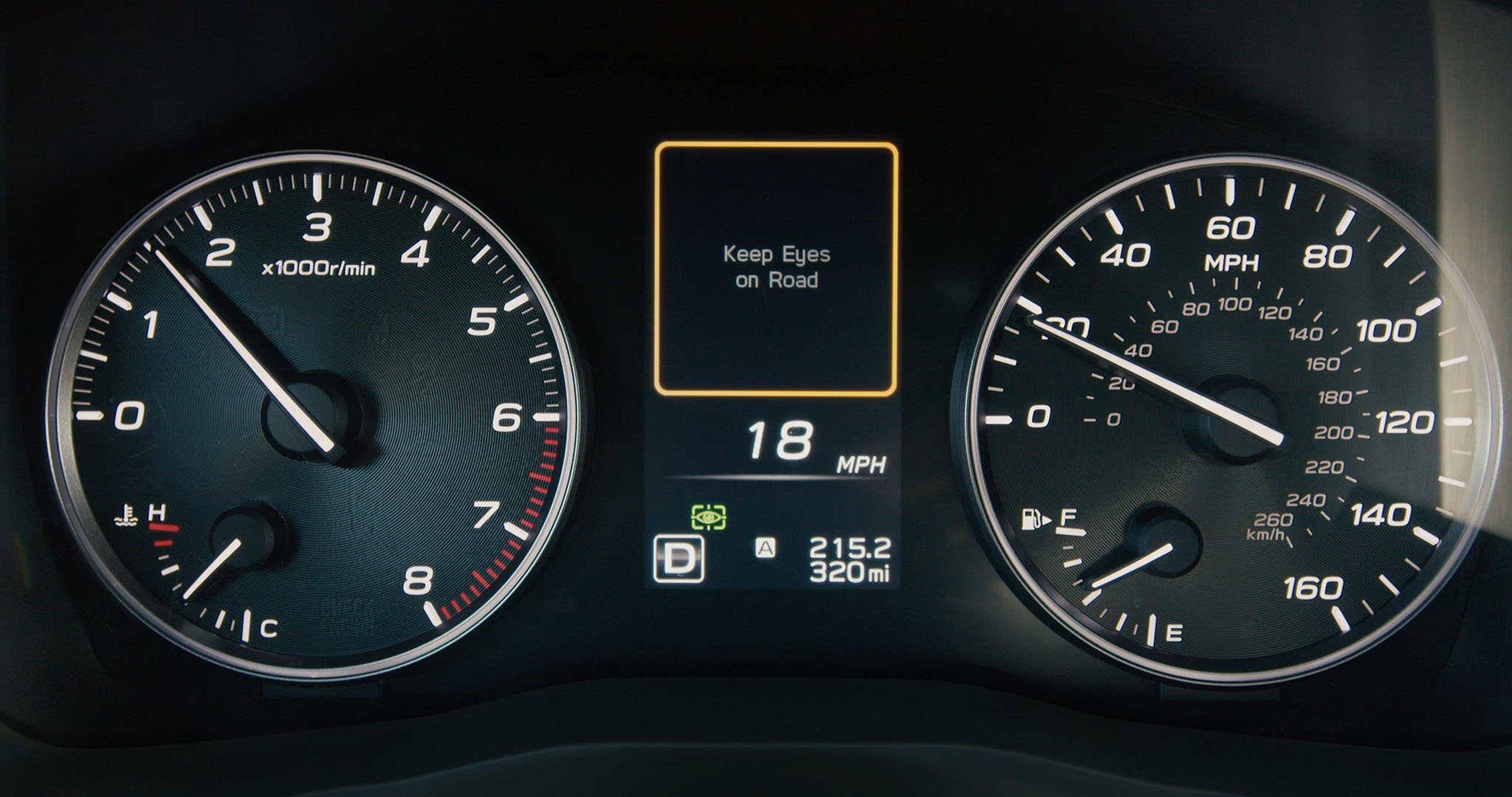 A Subaru dashboard display with a reminder prompting the driver to keep their eyes on the road.